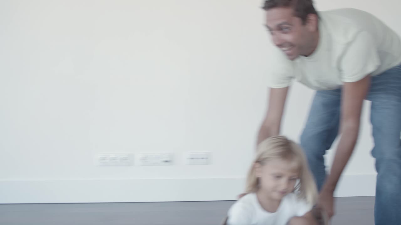 Cheerful dad dragging box with little daughter inside