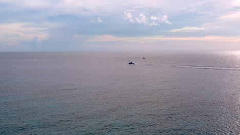 aerial 4k shot of a motorboat sailing on a calm sea from right to left. cloudy skies on the horizon.