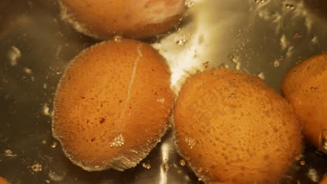 boiling eggs in steel pot with one egg crackled