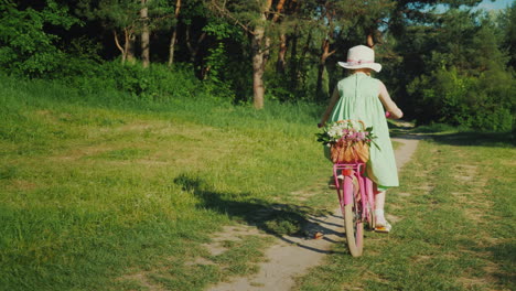 Ein-Mädchen-In-Einem-Grünen-Sommerkleid-Reitet-Einen-Waldweg-Entlang-Und-Trägt-Einen-Korb-Voller-Blumen