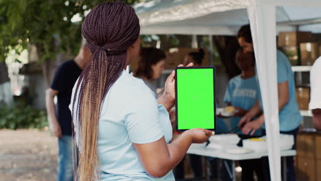 volunteer holds tablet with green screen