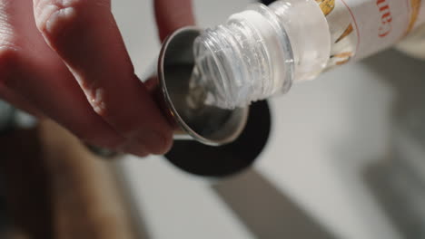pouring simple syrup into jigger and into cocktail shaker close up top shot