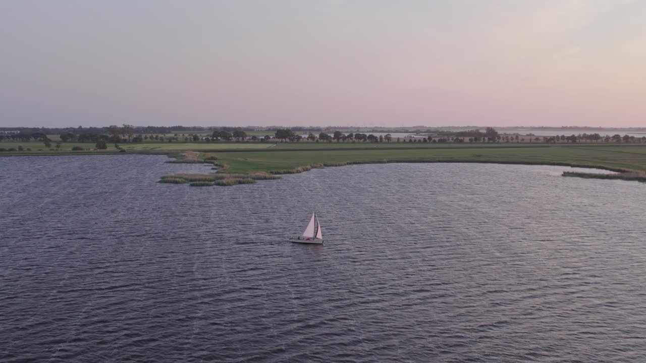 tomada panorámica de un buque de vela explorando el lago de friesland durante la puesta de sol, aérea