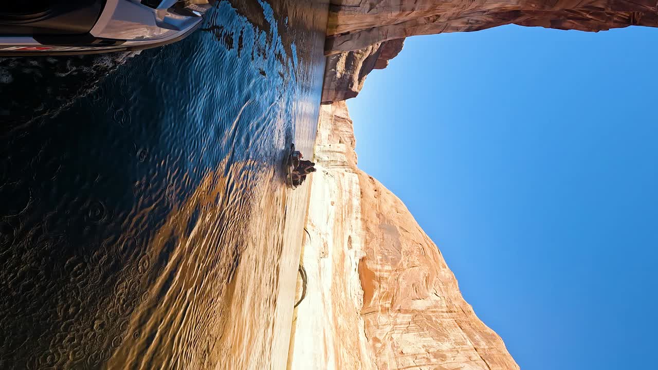 disparo vertical en cámara lenta de un patinete de agua que navega entre las rocas altas en el lago powell