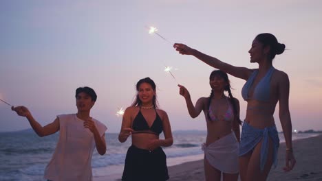 friends celebrating on the beach at sunset with sparkler