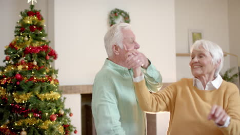 Feliz-Pareja-Caucásica-Mayor-Bailando-Junto-Al-árbol-De-Navidad-En-Casa,-Cámara-Lenta