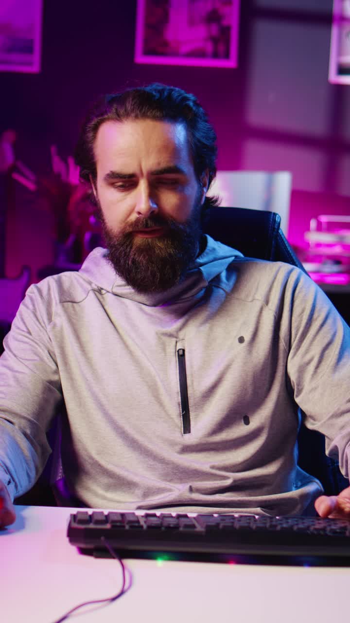 Video verticale: un uomo partecipa a un torneo online di videogiochi durante una diretta streaming con il pubblico, premendo ripetutamente i pulsanti di attacco