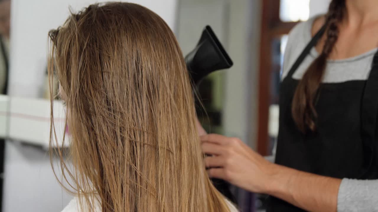 mujer secándose el cabello con un secador de pelo