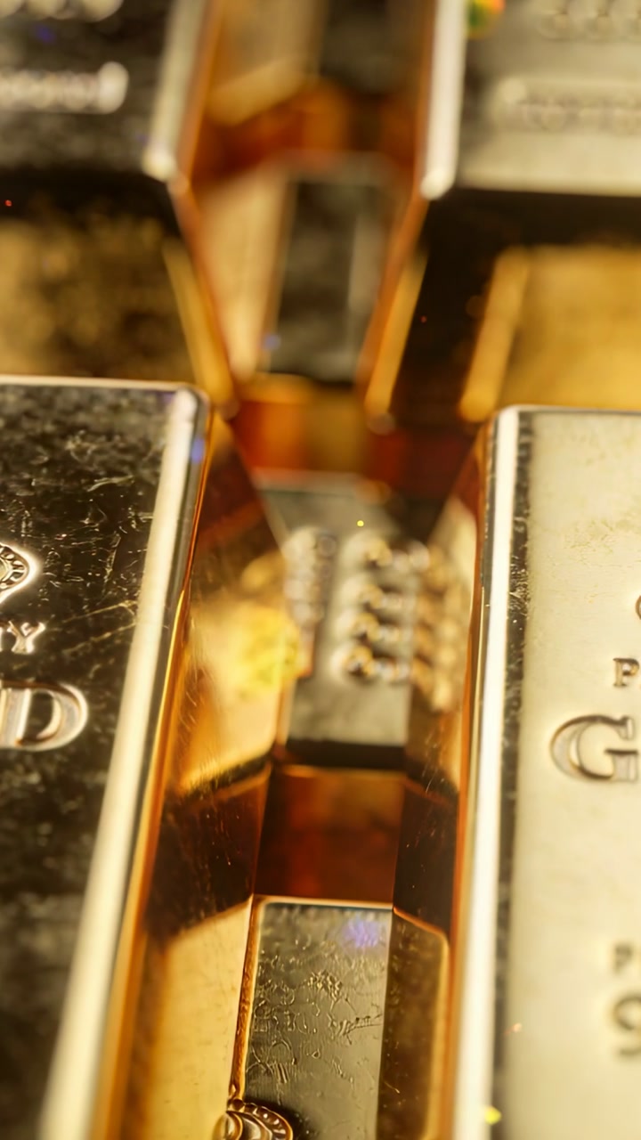 Vertical video: Panning camera sliding into stacked gold-bar gap in tray, revealing crown hallmark