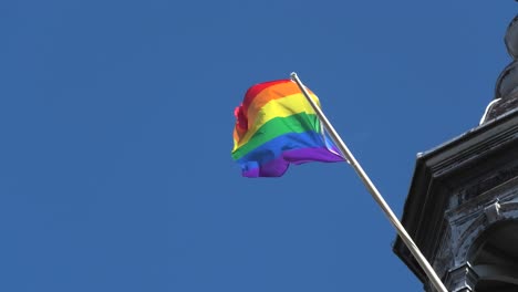 Bandera-Del-Arco-Iris,-Símbolo-Del-Orgullo-Gay-Ondeando-En-Lo-Alto-De-Un-Edificio