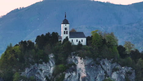 tomada de avión no tripulado de la capilla de johannesberg en la colina rocosa sobre el lago traunsee y el pueblo de traunkirchen, alpes austriacos