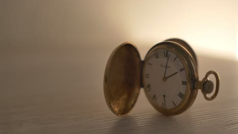 Static-shot-of-antique-pocket-watch-sitting-on-an-otherwise-empty-light-grey-desk