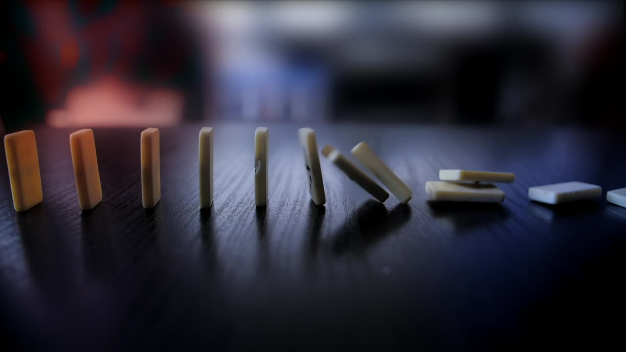 Domino che cadono a reazione a catena su un tavolo scuro