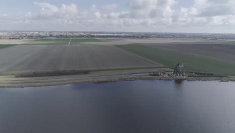 fast moving drone shot of dutch farmland with windmills and river