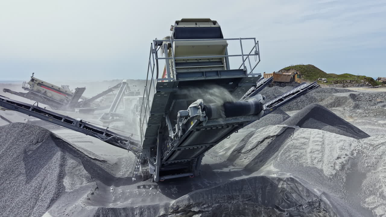 Granite quarry in operation with machinery processing stone and transporting material on a clear day