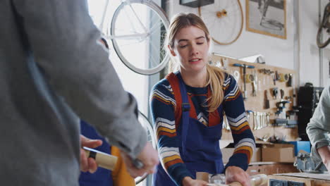 equipo multicultural de aprendices en un taller ensamblando el marco de una bicicleta construida a mano