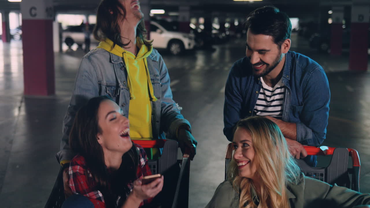 Close-up view of two Caucasian young girls sitting in a trolley and one girl showing to the other something on her smartphone screen while they laughing