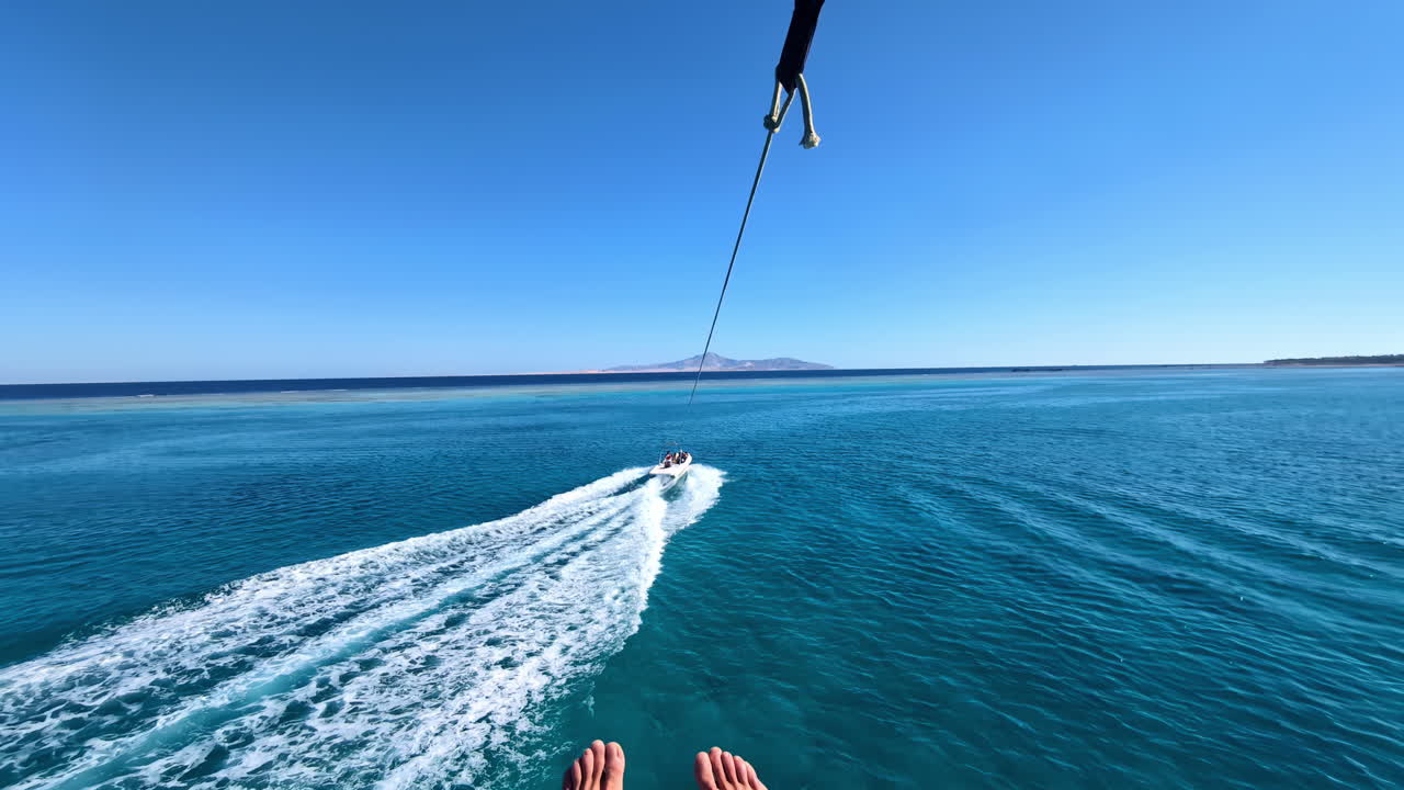 pov de planear con paracaídas sobre un hermoso mar, remolcado por un barco mientras hace parasailing