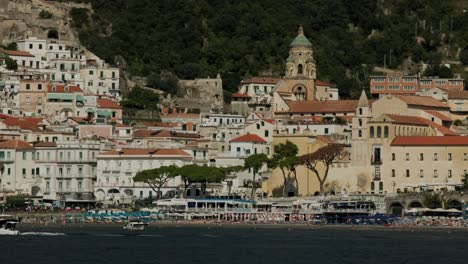 Pov-Desde-Un-Barco-Navegando-En-El-Mar-Con-La-Ciudad-De-Amalfi,-La-Catedral-Y-La-Playa-En-Italia