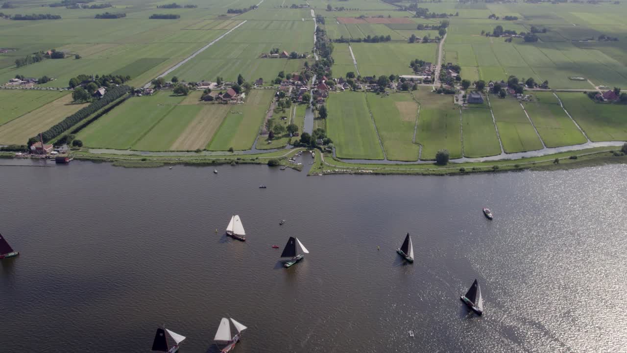 Vista aérea de veleros en el lago Tjeukemeer durante un evento en Echtenerbrug, Países Bajos, con una impresionante iluminación del amanecer, ambiente tranquilo e imágenes de dron de alta calidad que revelan un paisaje sereno.