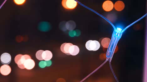 guirnalda de navidad con luces de colores junto a la ventana contra el fondo de la ciudad y el movimiento de los coches, primer plano. luces de navidad borrosas. bokeh.