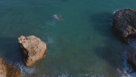 Incline-Hacia-Arriba-El-Clip-De-Drones-Aéreos-Que-Se-Mueven-Sobre-Una-Playa-De-Arena-Y-Una-Formación-Rocosa-En-Kavala,-Macedonia,-Grecia