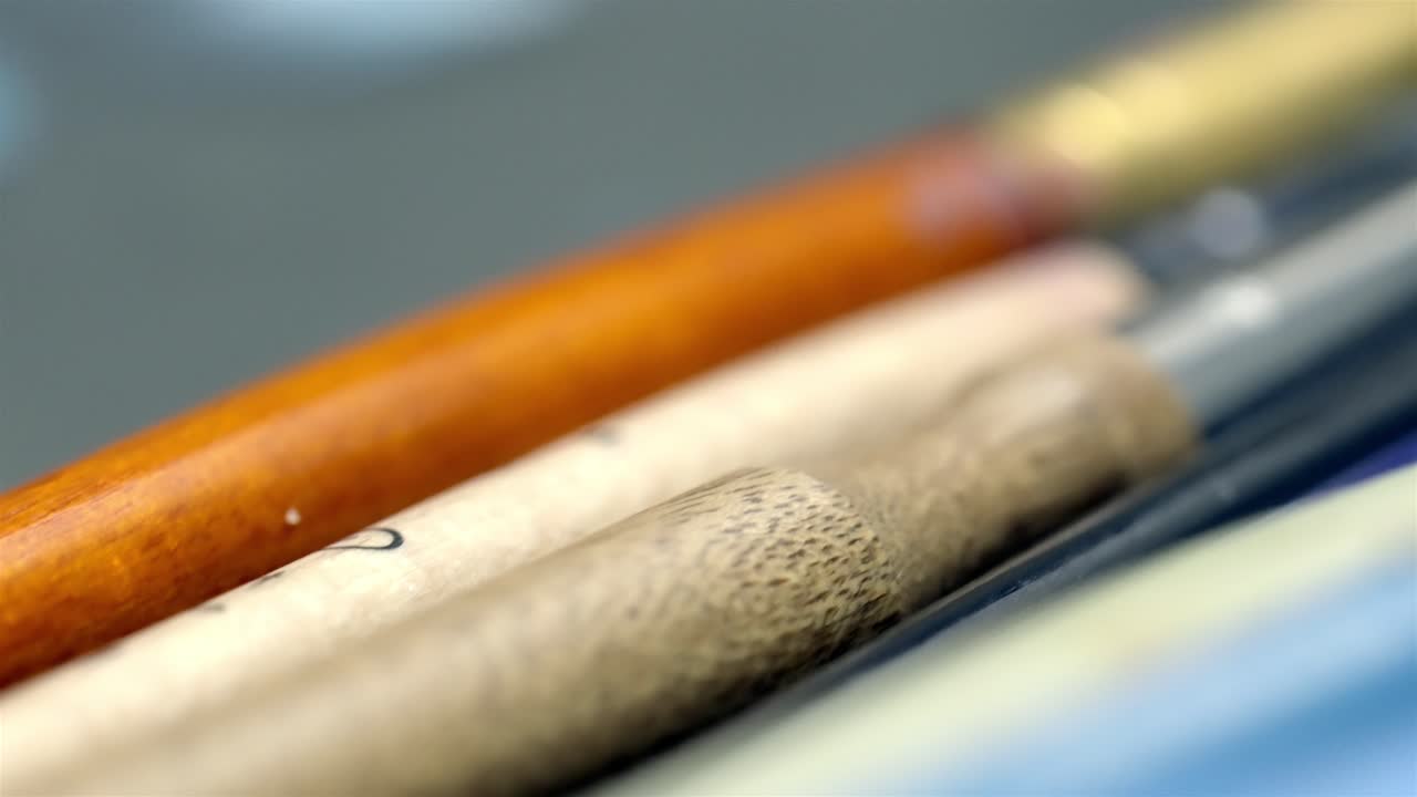Pennelli da artista appoggiati su un tavolo da studio, messa a fuoco macrofotografica.
