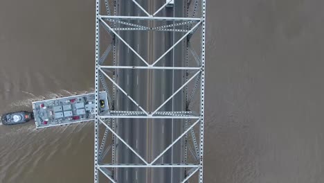 aerial: overhead birds eye view of bridge and traffic, with a construction boat passing underneath