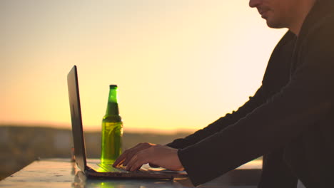 Hipster-man-with-a-laptop-on-the-edge-of-the-roof.-Freelancer-at-work.-Wireless-mobile-Internet.-He-works-on-the-Internet.