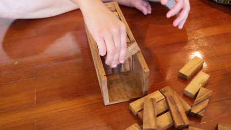 hands playing and toppling a wooden jenga tower