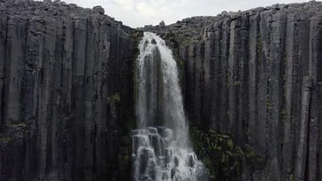 drone volando hacia arriba filmando una cascada y las montañas sobre ella en islandia 4k