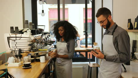 african american female barista and caucasian male coworker working in modern coffee shop