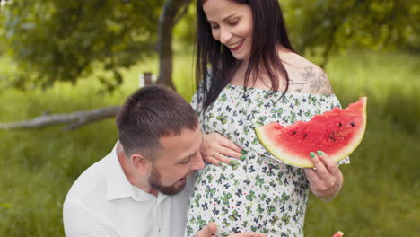 pregnant couple enjoying watermelon in the garden