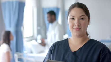 portrait of caucasian female doctor using tablet and smiling in ward, copy space, slow motion