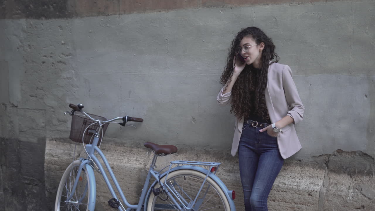 Young woman talking on phone next to a vintage bicycle.