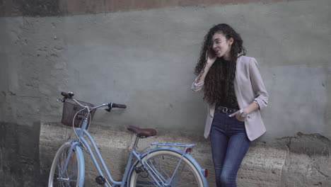 young woman talking on phone next to a vintage bicycle.