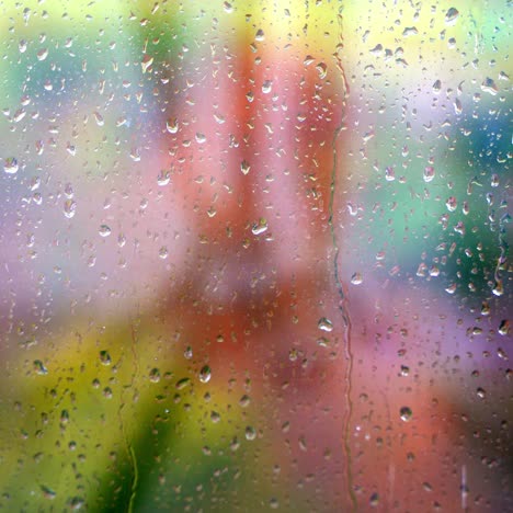 droplets of water on enlighted colored glass background. rain water drops running down. water droplets falling on glass surface