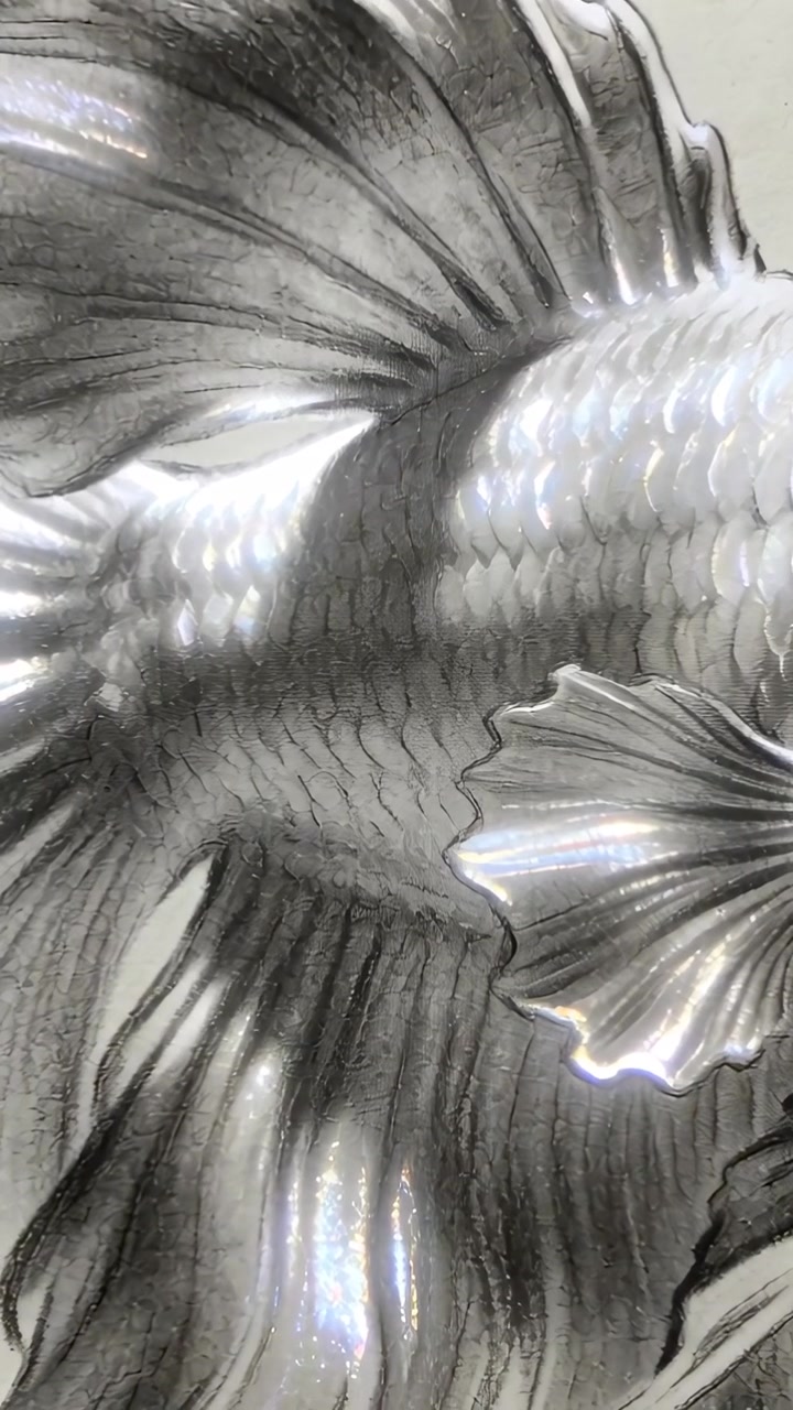 Video verticale: Luce della lampada che si sposta, rivelando un disegno di pesce a grafite sulla scrivania, per mostrare una lucentezza perlacea.