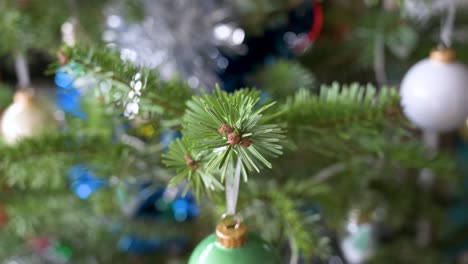 Close-up-and-shallow-focus-view-of-detailed-Christmas-pine-tree-branches-adorned-with-numerous-ornaments-during-the-winter-season