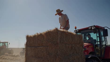 farmer working on hay bales with tractors
