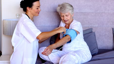 enfermera en el hogar comprobando la presión arterial de los pacientes