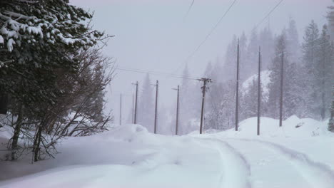 nieva en una carretera con huellas de vehículos visibles y un grupo de líneas eléctricas