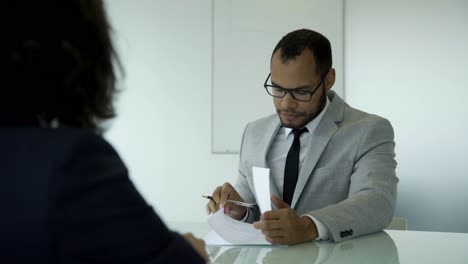 un joven guapo y seguro de sí mismo firmando documentos.