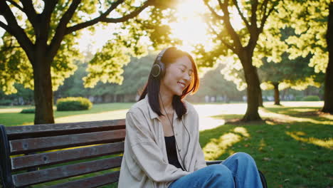 young woman enjoying music with headphones in a sunny park