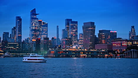 dazzling lights in the skyline of modern new york at dusk time. riverboat travels by the river slowly
