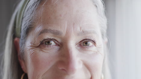 Portrait-of-happy-middle-aged-caucasian-woman-by-window-at-home-with-copy-space