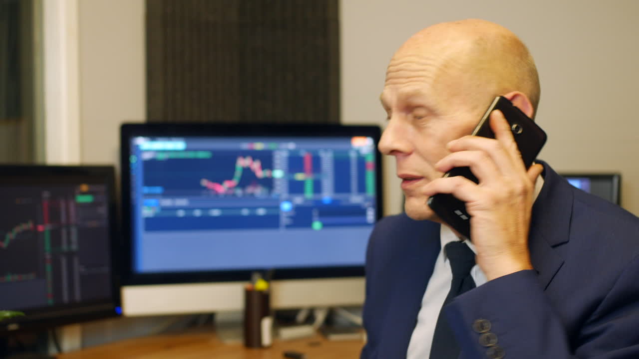 Un uomo d'affari maturo stressato che parla al telefono in un ufficio di brokeraggio