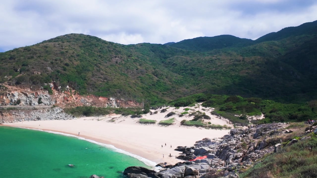 En motorsyklist utforsker Dak Lak i Vietnam og nyter en motorsykkeltur langs en strand. Området har åser og en klar himmel, noe som gir vakker utsikt over naturen