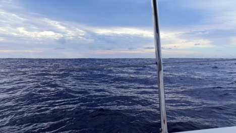 ocean waves shimmer under soft sunset light seen from deck of a sailing yacht