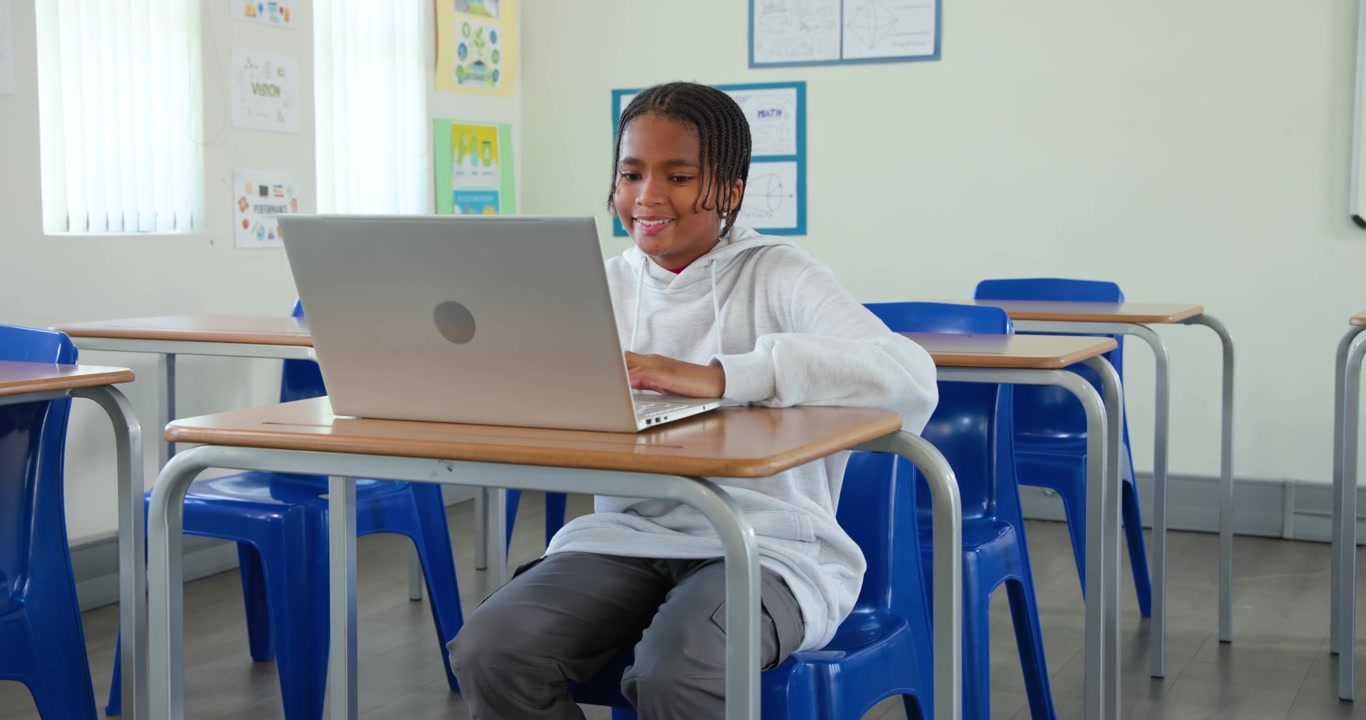 Giovane studente africano seduto al banco in classe, che digita sul laptop, guarda, si strofina la testa e studia